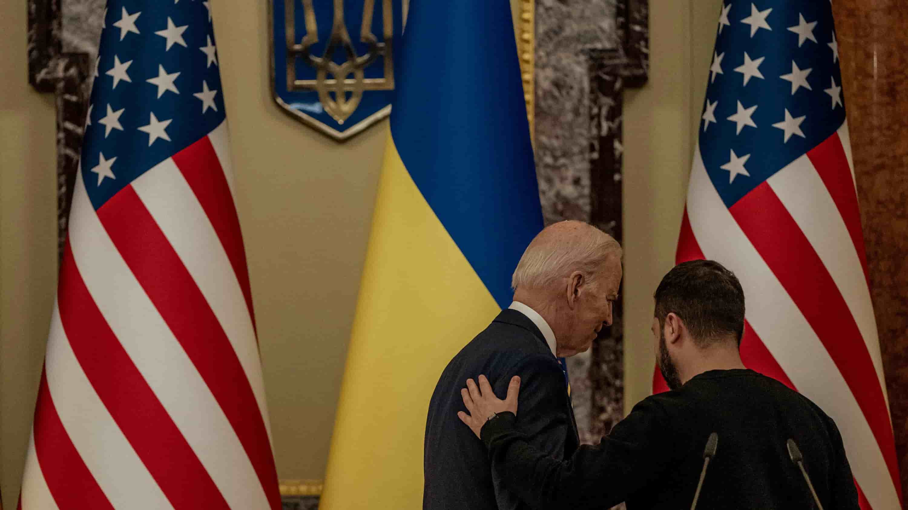 Joe Biden and Volodymyr Zelenskyy engage in a discussion amidst the flags of the United States and Ukraine, signaling a diplomatic dialogue regarding the ongoing conflict in Ukraine.